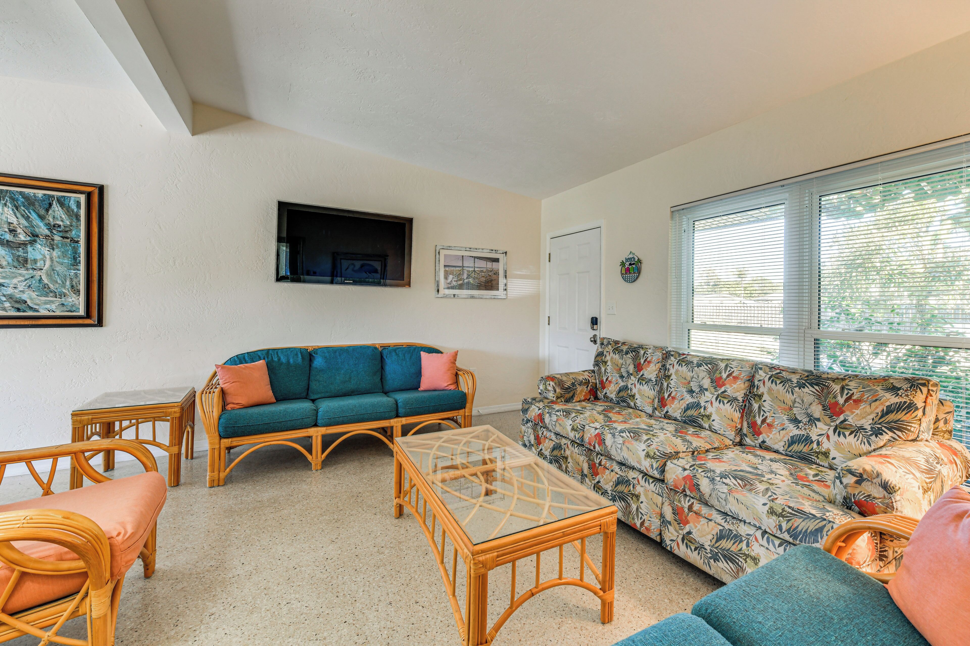A living room with two sofas, a glass-top coffee table, and wicker chairs.