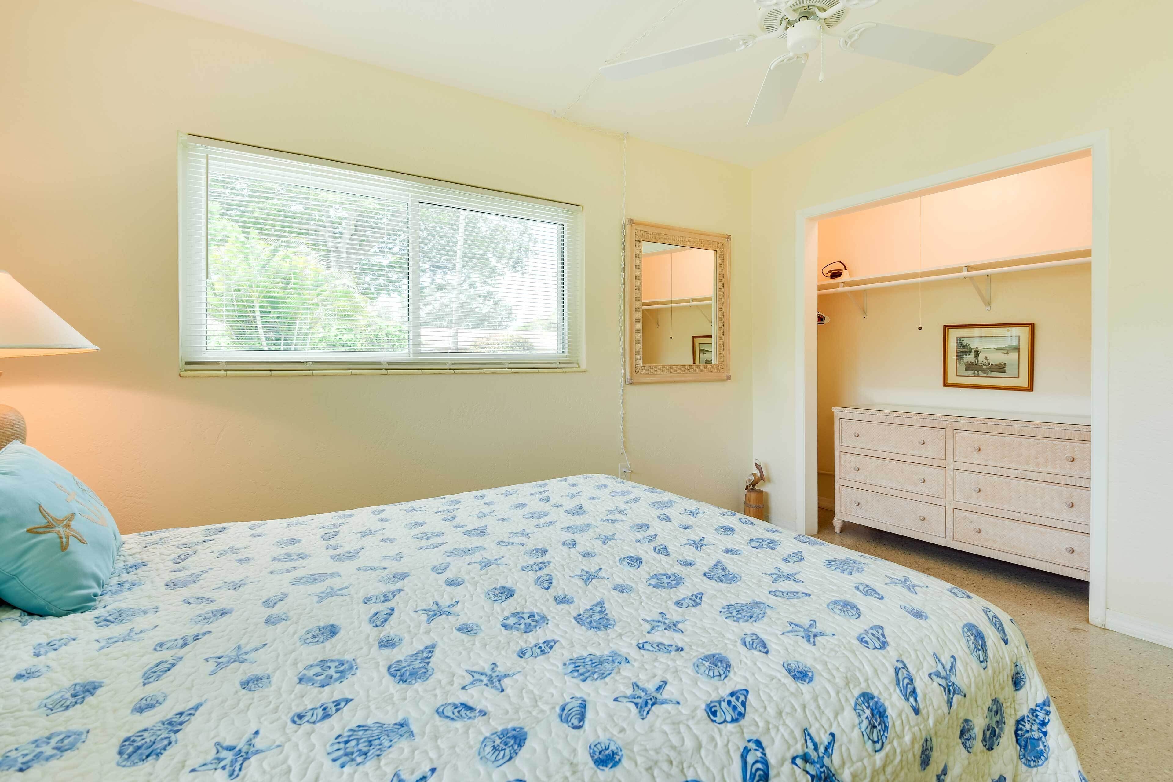 Un dormitorio con cama, cómoda, espejo y ventana con persianas.