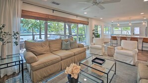 Un salon spacieux avec un canapé beige, une table basse en verre et une vue sur l’extérieur.