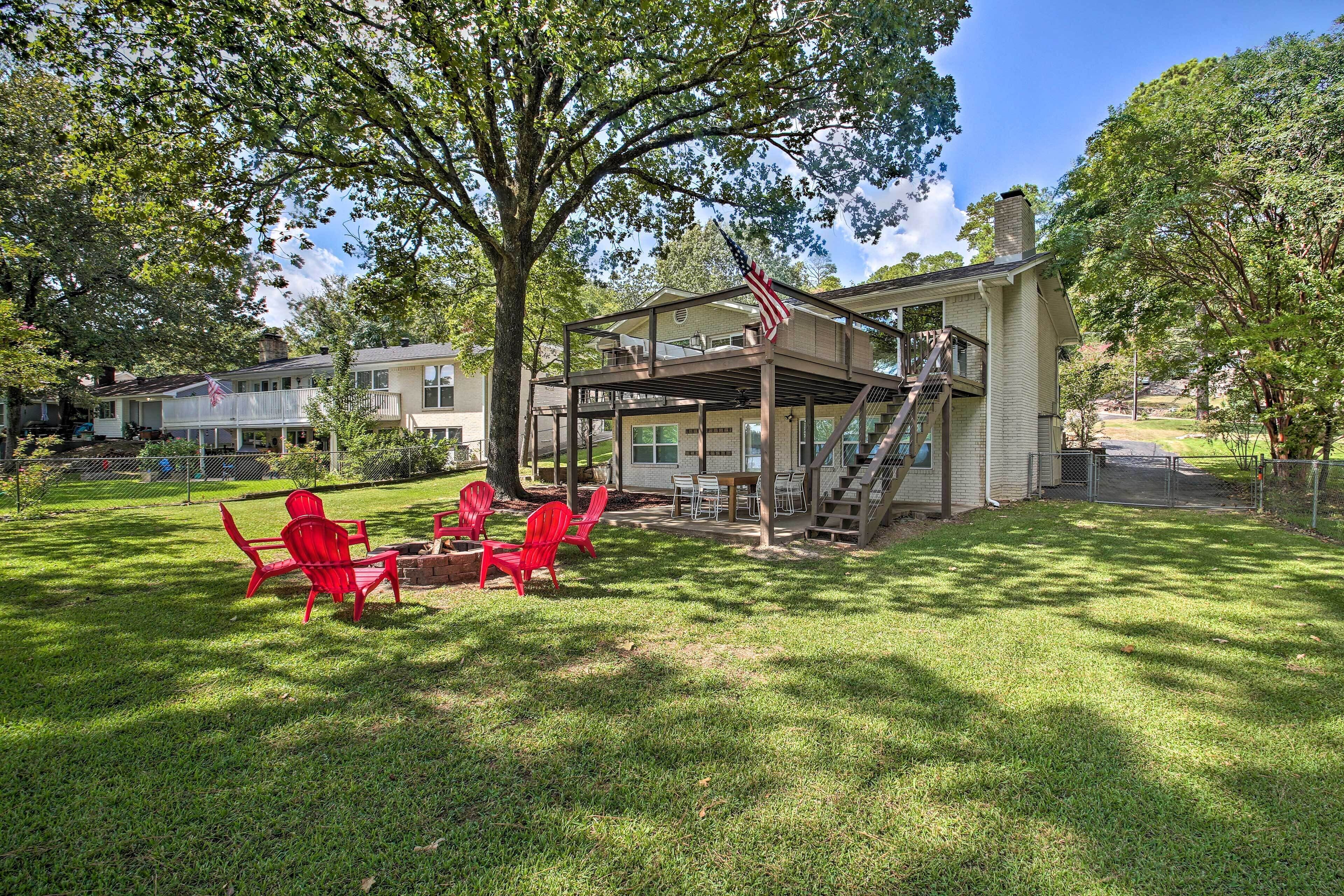 A two-story house with a covered porch, a flag, and red Adirondack chairs in the yard.