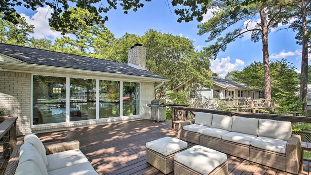 Une terrasse dotée de meubles en osier, d’un barbecue et d’un espace patio fermé par des baies vitrées.