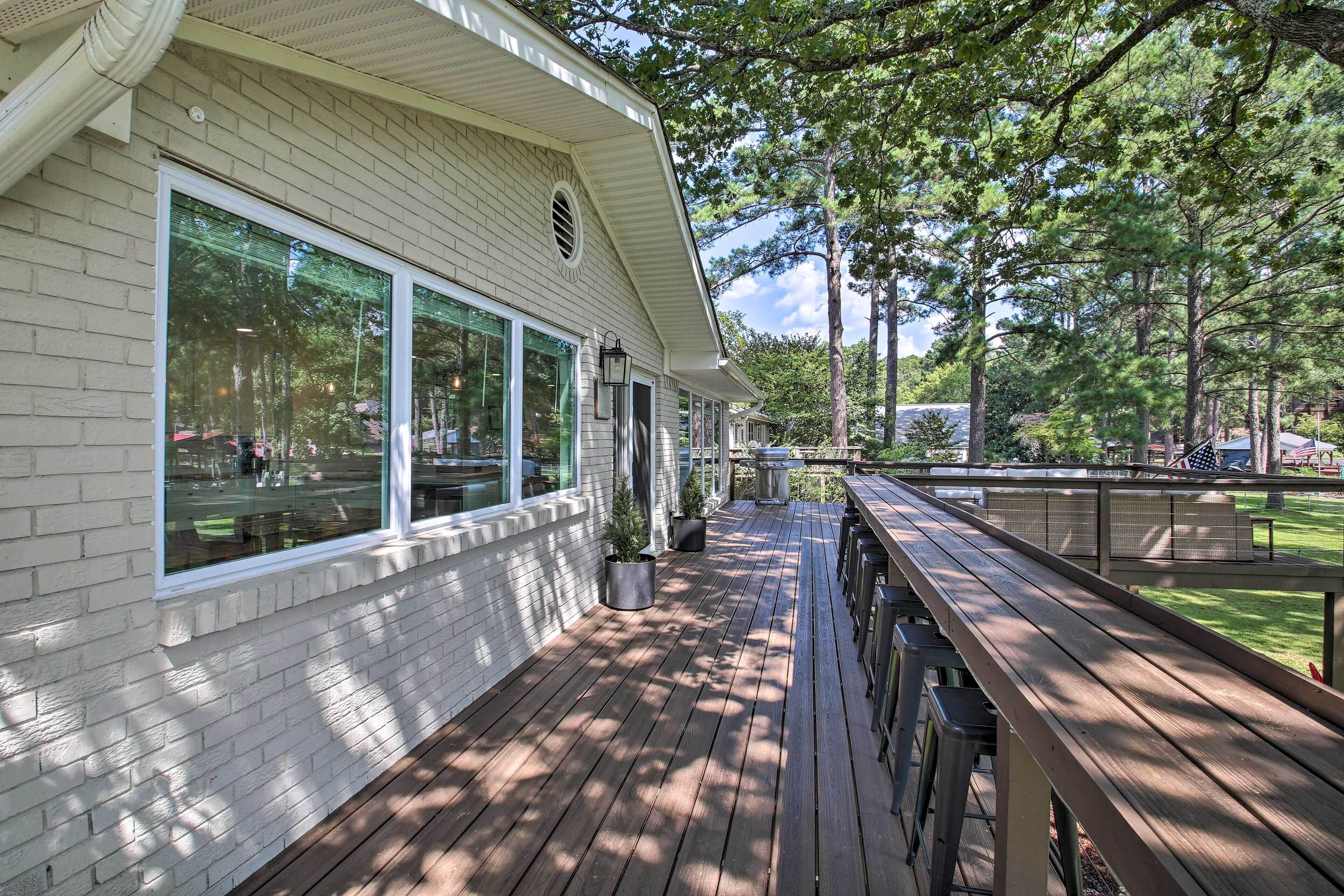 A covered deck with wooden flooring, large windows, and outdoor seating.