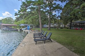Um deck à beira do lago com espreguiçadeiras, um pequeno píer e um gazebo.