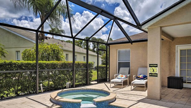A swimming pool with a hot tub, surrounded by a covered patio with chairs and a caution sign. - Saltwater Pool, Spa & Lanai: Bradenton Home (Bradenton)