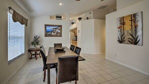 A dining area with a long table, chairs, a ceiling fan, and a painting on the wall. - Saltwater Pool, Spa & Lanai: Bradenton Home (Bradenton)