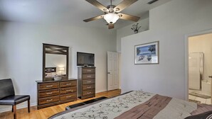A bedroom with a bed, a dresser, a chair, a ceiling fan, a TV, and a door. - Saltwater Pool, Spa & Lanai: Bradenton Home (Bradenton)