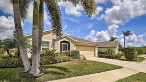 A residential house with a well-maintained lawn, palm trees, and a clear blue sky. - Saltwater Pool, Spa & Lanai: Bradenton Home (Bradenton)