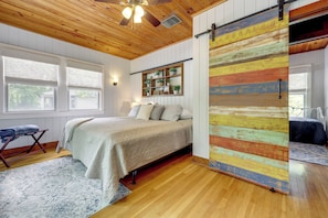 A bedroom with a bed, a wooden ceiling, a sliding barn-style door, a window, and a shelf with plants. - Spacious Lake Placid Retreat w/ Gorgeous Views! (Seguin)