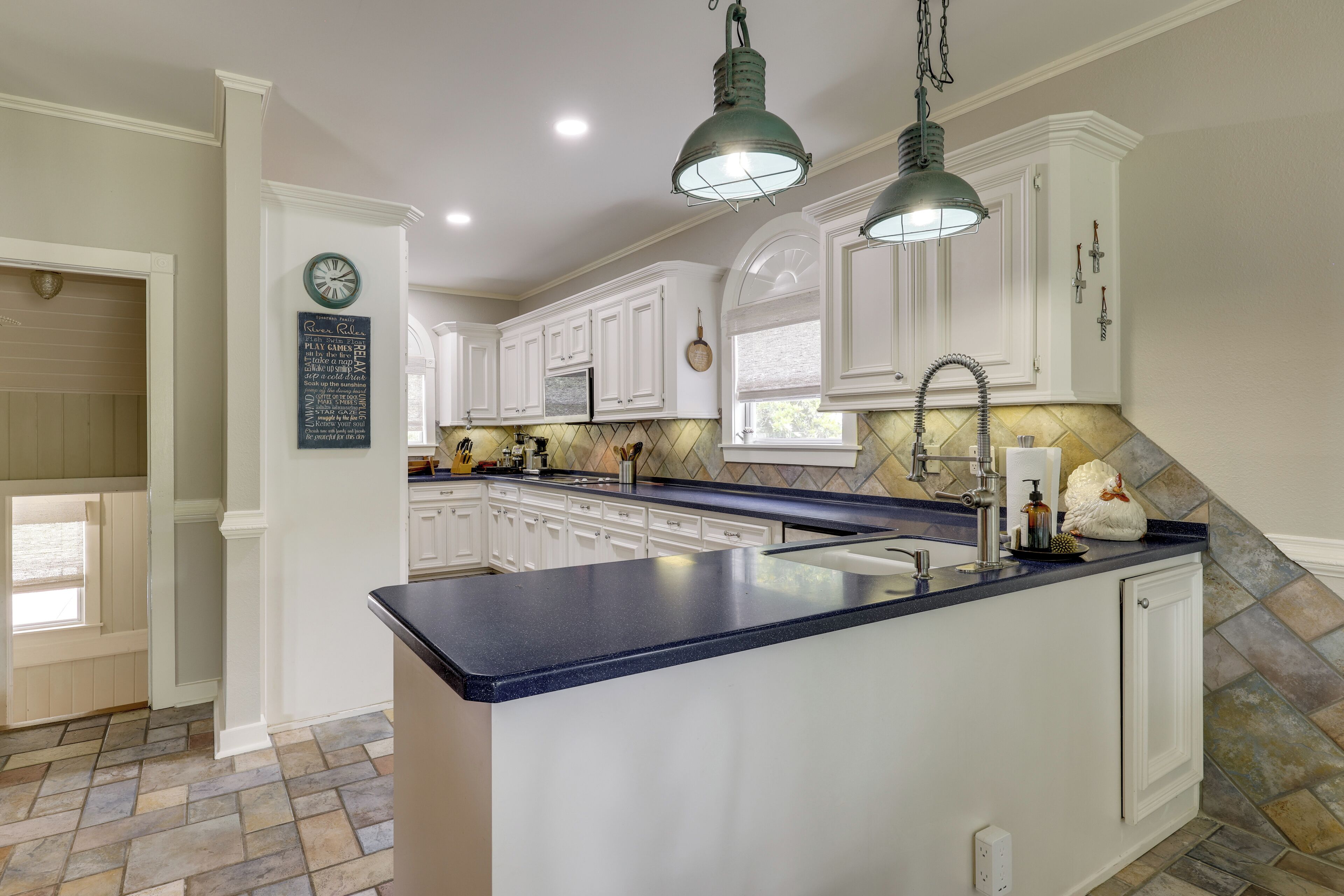 A kitchen with white cabinets, a blue countertop, and a stone backsplash.
