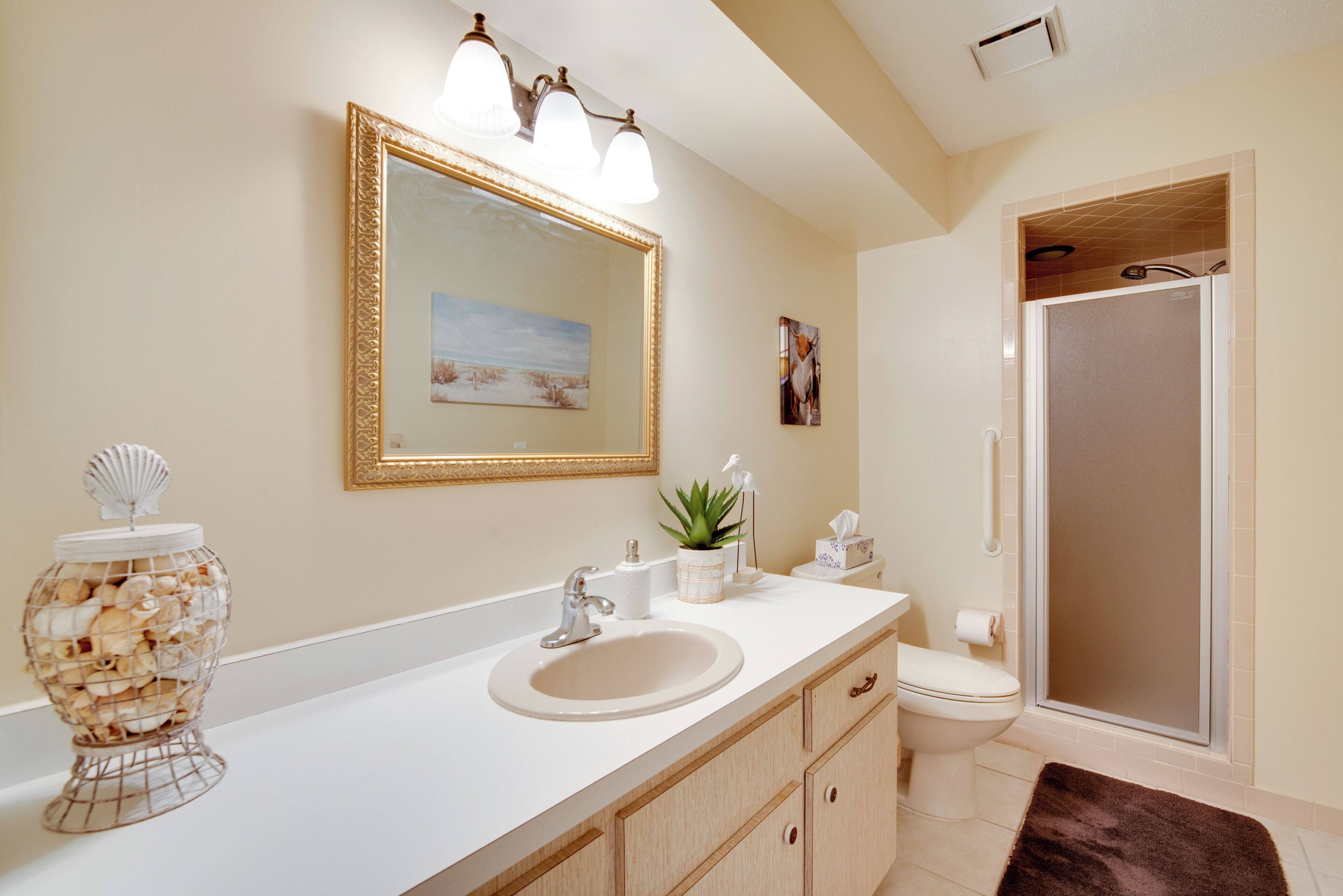 A bathroom with a sink, mirror, toilet, and shower.