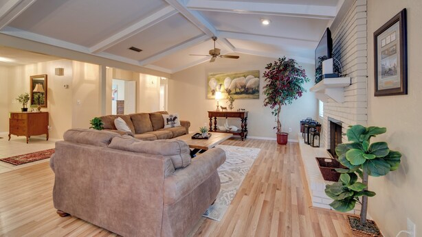 A spacious living room with a large sofa, a coffee table, and a fireplace. There is a ceiling fan and a large window providing natural light. - Getaway < 9 Mi to Historic Downtown Ocala (Ocala)