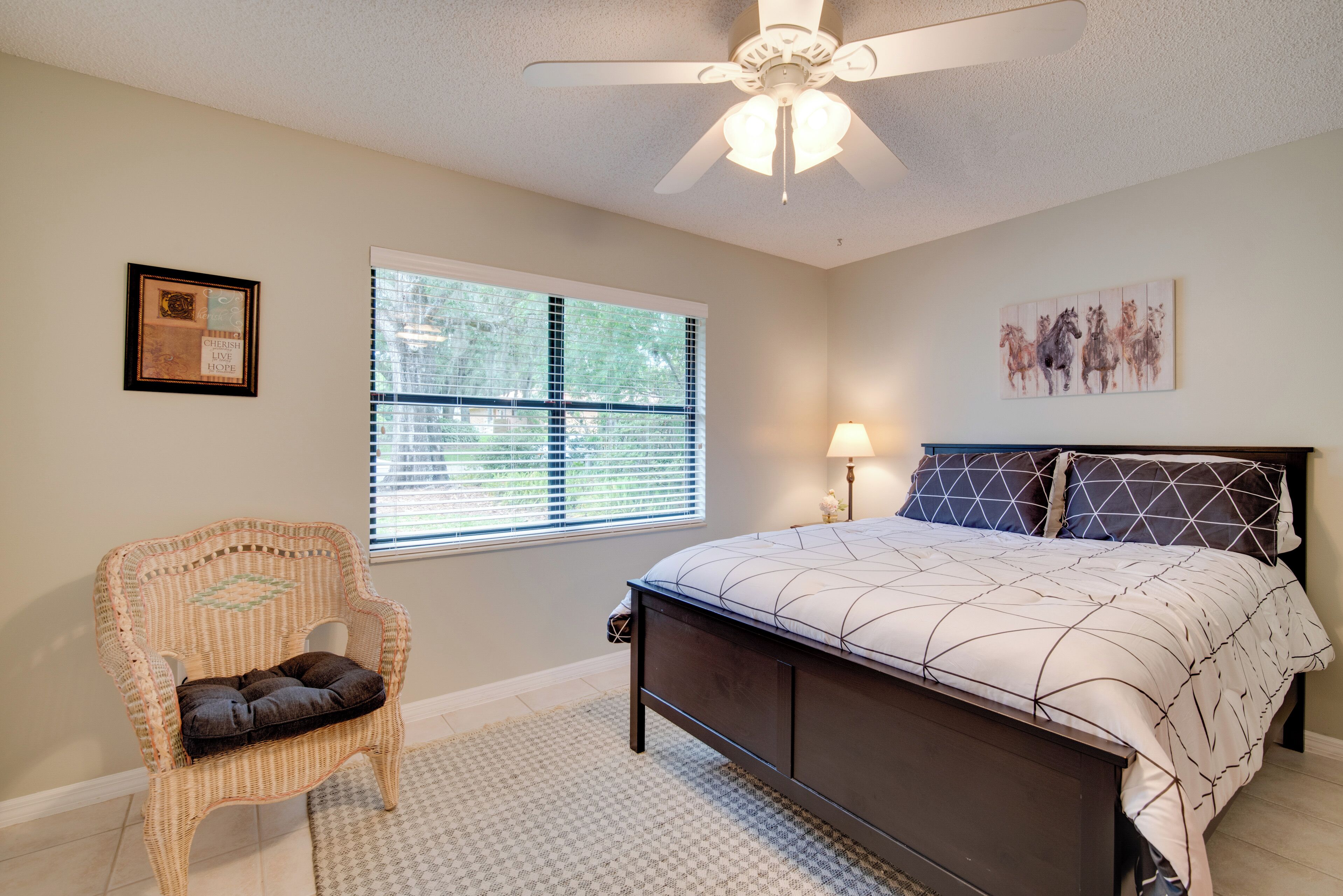A bedroom with a bed, a chair, a window, and a ceiling fan.