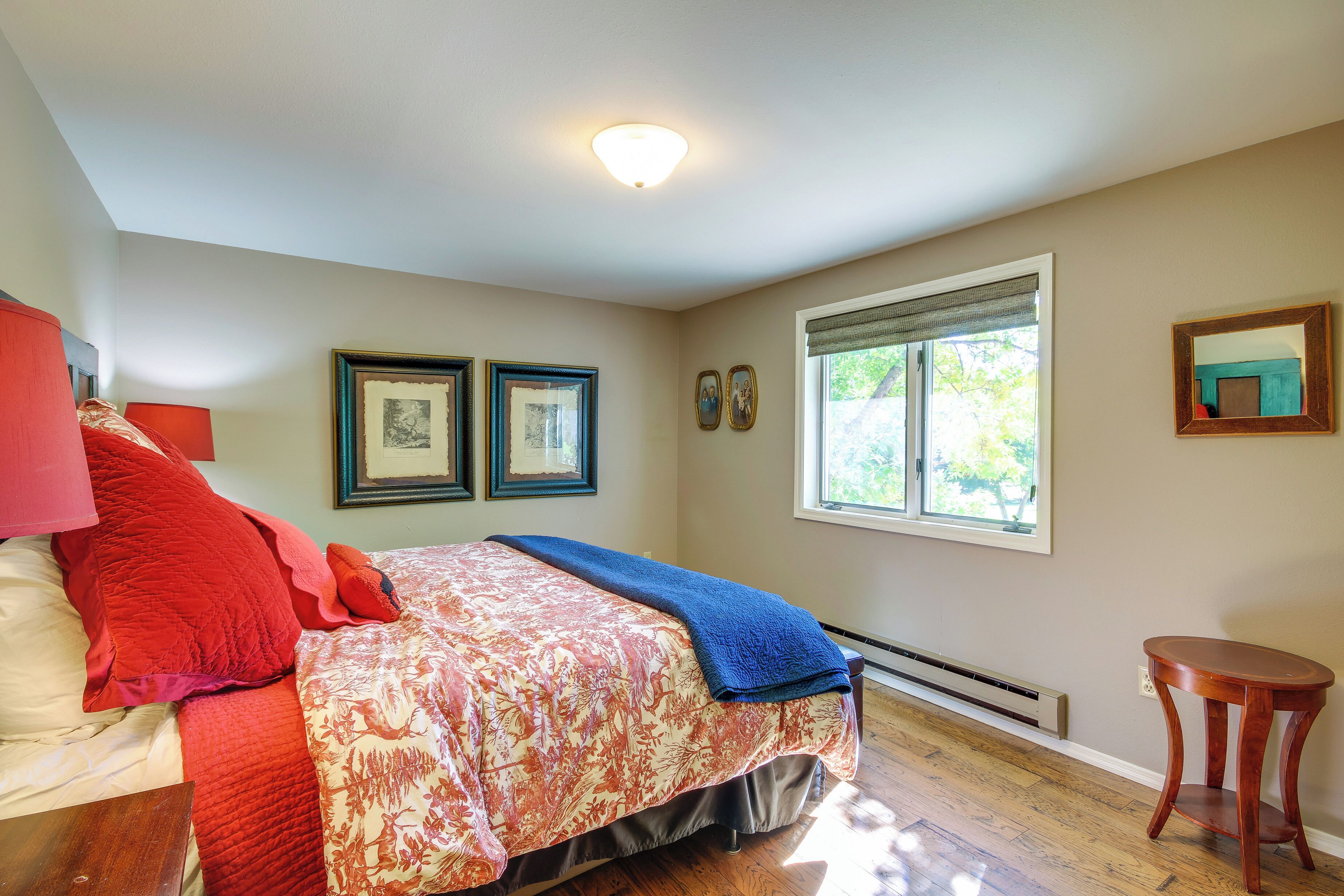 A bedroom with a bed, a heater, a window with blinds, and a small table.