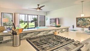 A modern kitchen with a gas stove, a ceiling fan, and a large window overlooking a garden. - Lush Molokai Island Oasis w/ Private Pool + Beach! (Kaunakakai)