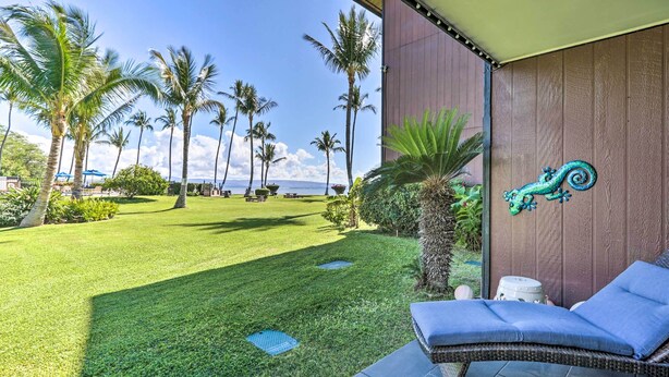 A patio with a lounge chair, a decorative wall, and a view of the ocean. - Lush Molokai Island Oasis w/ Private Pool + Beach! (Kaunakakai)