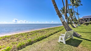 A bench on a grassy area with a view of the ocean and palm trees. - Lush Molokai Island Oasis w/ Private Pool + Beach! (Kaunakakai)