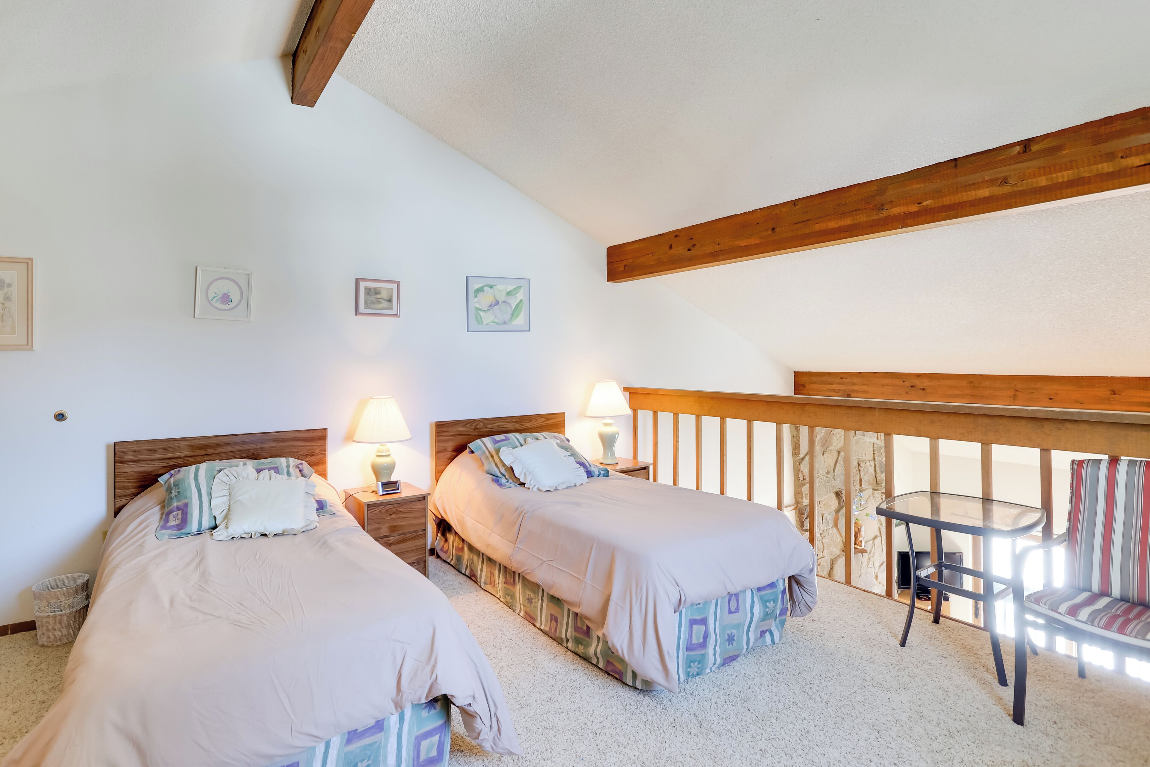 A bedroom with two beds, a small table, and a chair.