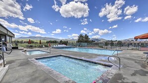 Un área de piscina con varias piscinas, sillones reclinables y sombrillas.