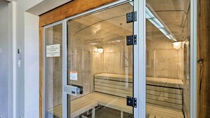 Un baño de vapor con un banco de madera, un panel de control y una señal que indica restricción de edad.