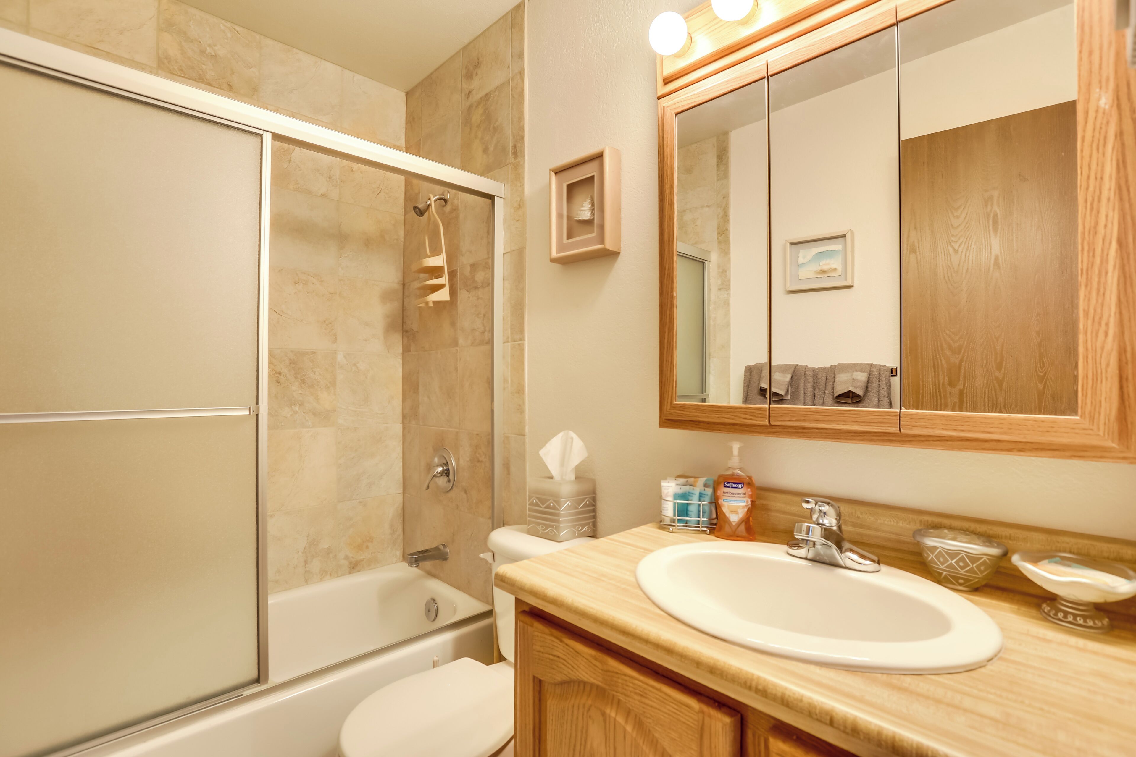 A bathroom with a bathtub, toilet, sink, and a large mirror.