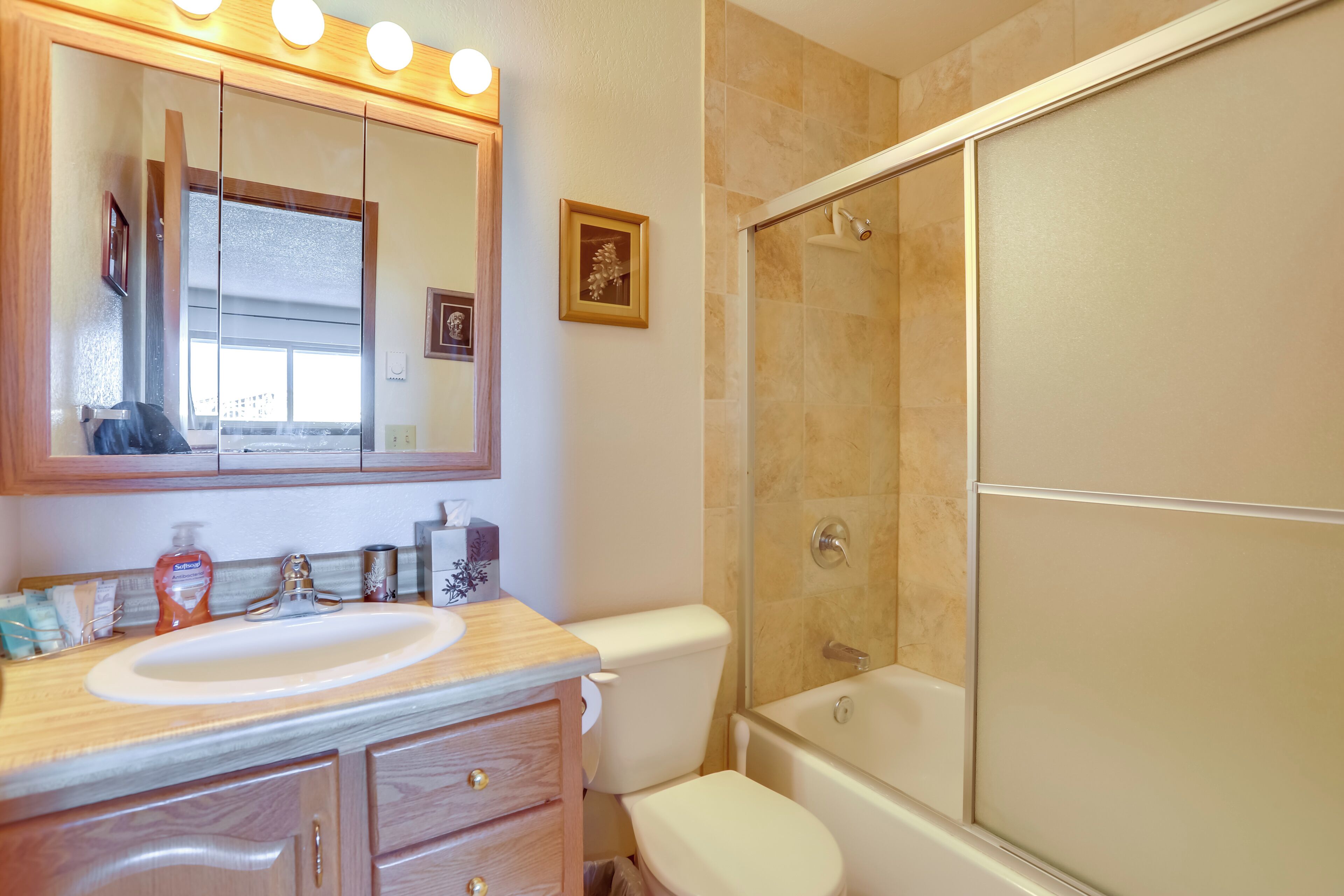 A bathroom with a sink, mirror, toilet, and shower.