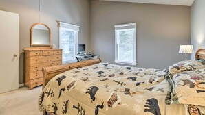 A bedroom with a large bed, a wooden dresser, a mirror, and two windows. - Massanutten Retreat w/ Double Deck & Mtn View! (McGaheysville)