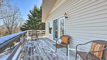 A wooden deck with a railing, a table with chairs, and a bench with cushions.