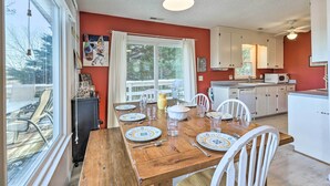 A dining area with a wooden table set for six, white chairs, and a window overlooking a deck. - Massanutten Retreat w/ Double Deck & Mtn View! (McGaheysville)