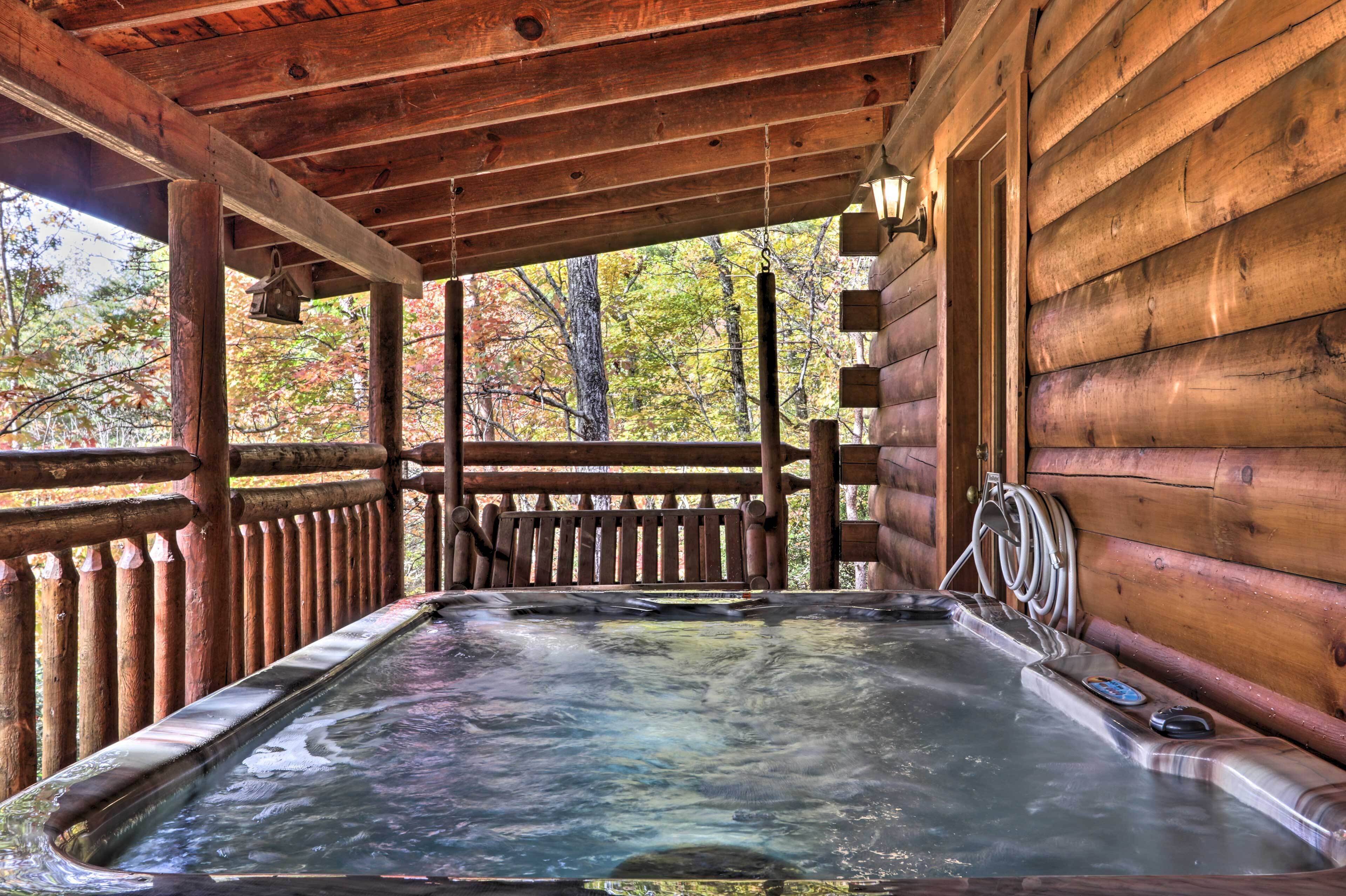 Eine Holzhütte mit Whirlpool unter einer Veranda.