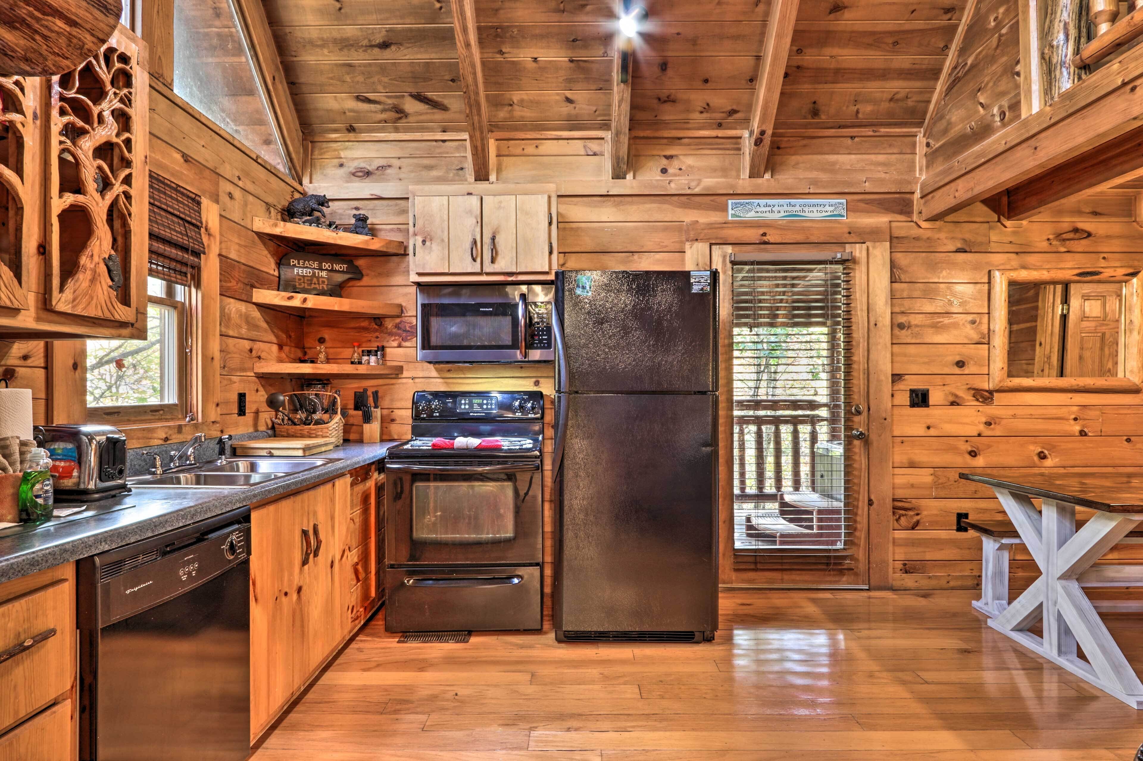 A wooden cabin kitchen with a refrigerator, stove, microwave, and dishwasher.