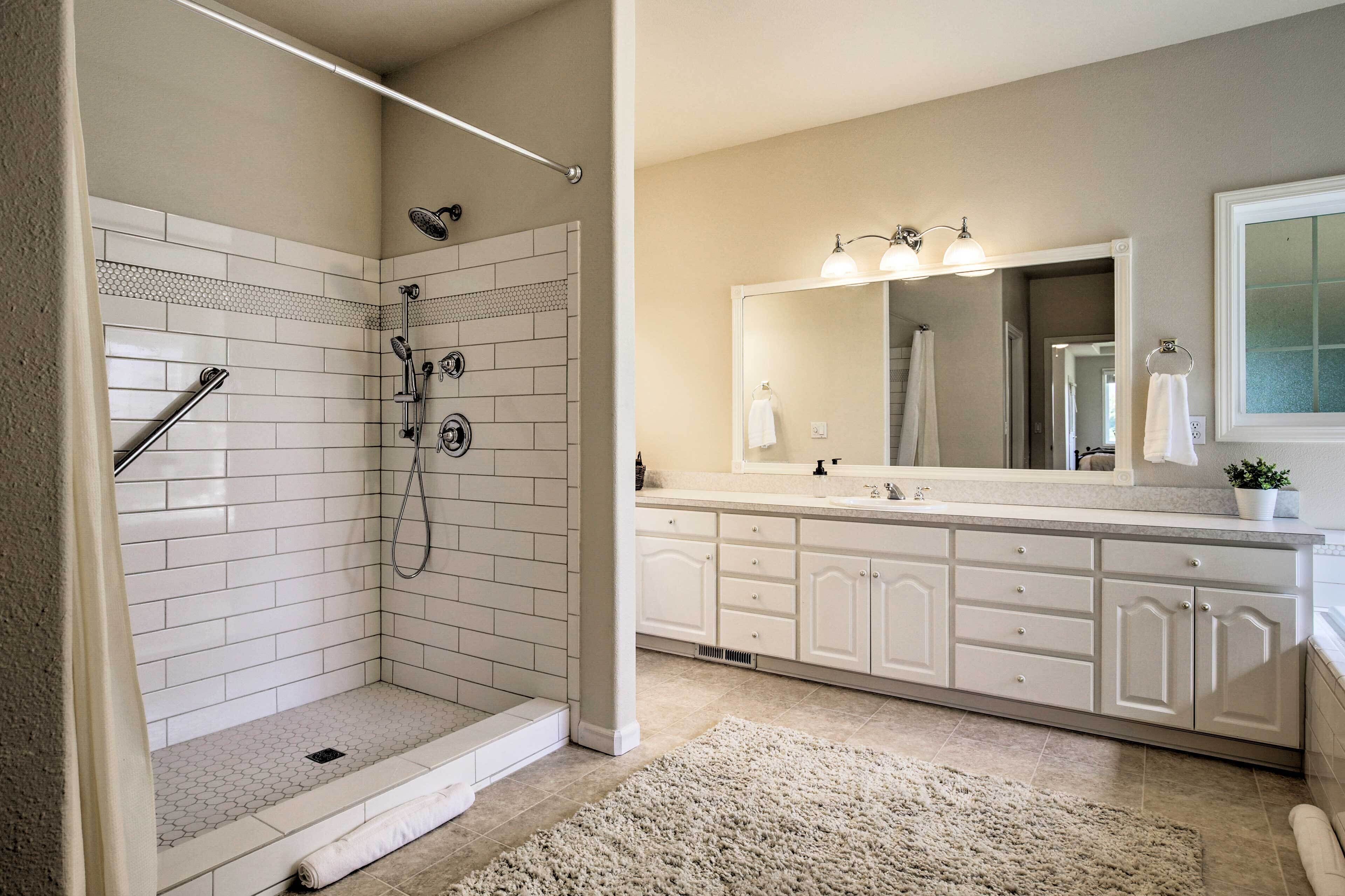 A modern bathroom with a walk-in shower, a large mirror, and a vanity with a sink.