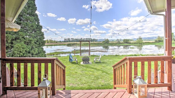 A wooden deck with a view of a lake, chairs, and a fire pit. - Mcminnville Wine Country Home w/ Hot Tub + Deck (McMinnville)