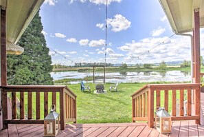 Una terraza de madera con vistas a un lago, sillas y una fogata.