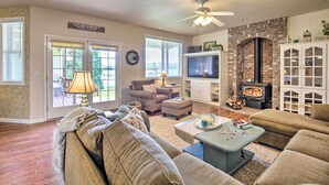 A cozy living room with a fireplace, comfortable seating, and a television. - Mcminnville Wine Country Home w/ Hot Tub + Deck (McMinnville)