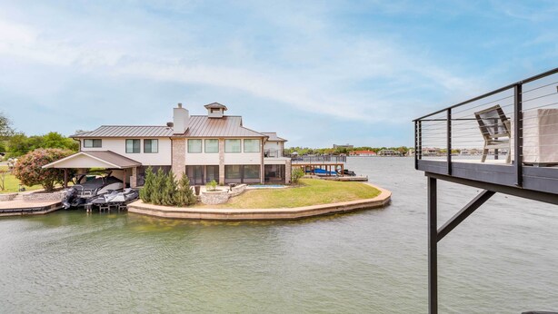 Une maison avec un quai et des bateaux, un patio couvert et une vue sur un plan d’eau.