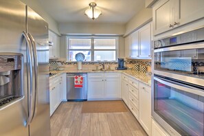 A modern kitchen with stainless steel appliances, white cabinetry, a large window, and a checkered backsplash. - Waterfront Home w/ Dock on Lake Lyndon B Johnson! (Horseshoe Bay)