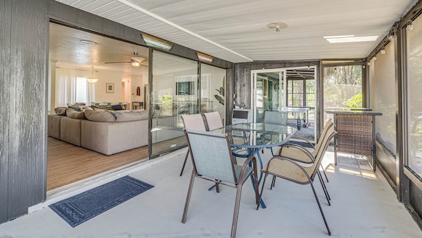 Een moderne woonkamer met een glazen wand, een bank en een eethoek met stoelen en een tafel.