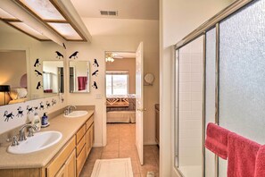 Un baño con dos lavamanos, un espejo y una zona de ducha.