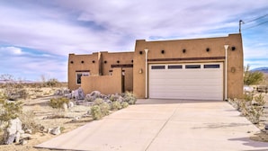 A single-story house with a garage, surrounded by a desert landscape.