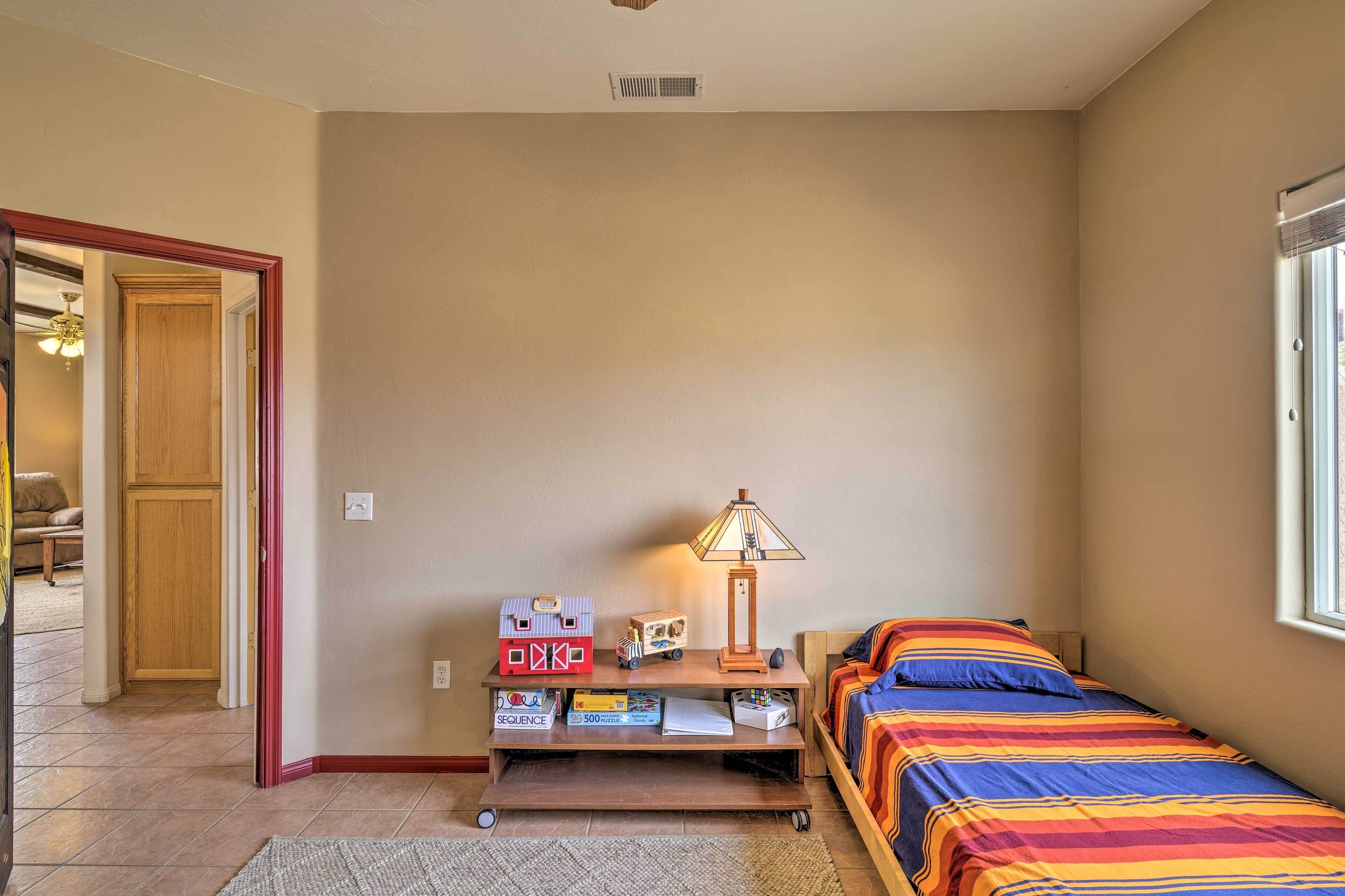 Un dormitorio con cama, escritorio con lámpara, ventana y puerta.