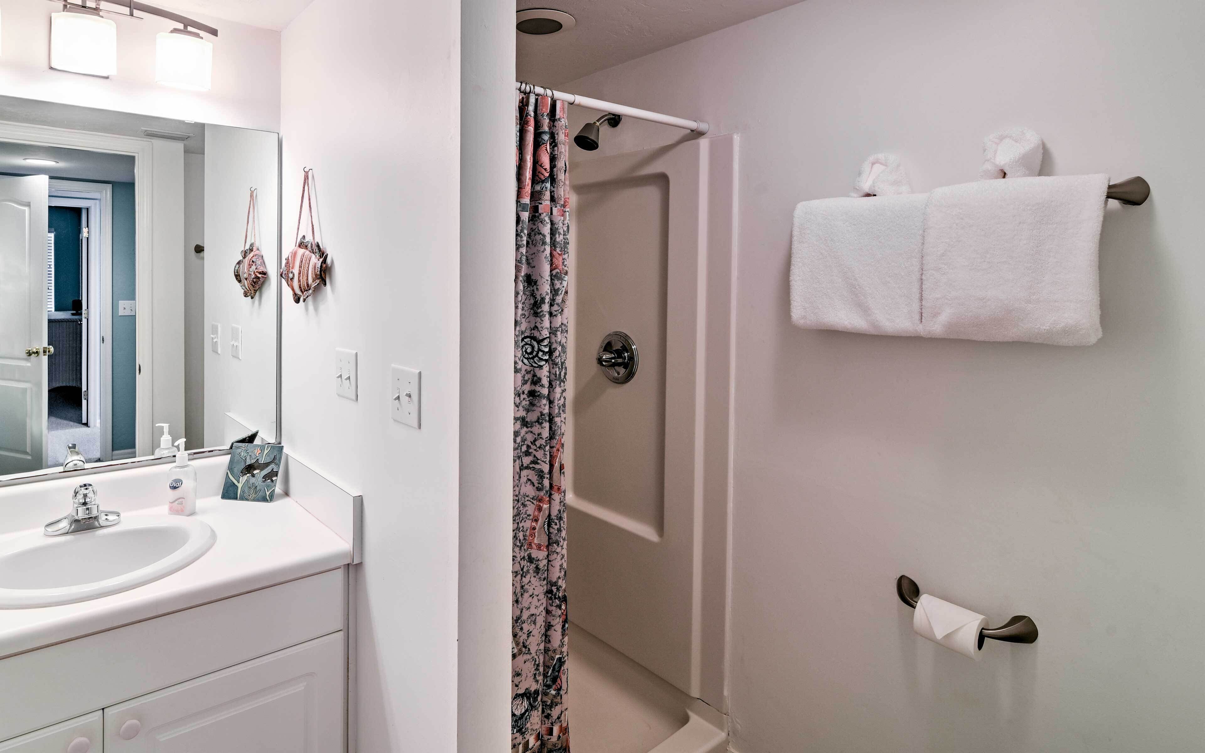 A bathroom with a white sink, mirror, shower curtain, and towel rack.
