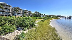 A beachfront hotel with multiple balconies, a sandy beach, and a clear blue sky. - Beachfront Cedar Key Condo w/ Pool, Spa & Views! (Cedar Key)