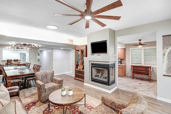 A spacious living room with a fireplace, a dining area, and a kitchen.
