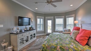 Ein Schlafzimmer mit Bett, Fernseher, Deckenventilator und Fenster.