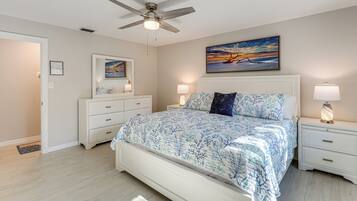 A bedroom with a bed, nightstands, a ceiling fan, a painting, and a white dresser.