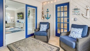 A room with two wicker chairs, a patterned rug, and nautical-themed decor including an anchor and a sign that reads "Come with me to the sea." - Indian Rocks Beach Home - 2 Blocks to Beach! (Indian Rocks Beach)