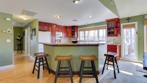 Une cuisine moderne dotée d’un îlot central, de tabourets en bois et de meubles de rangement rouges.