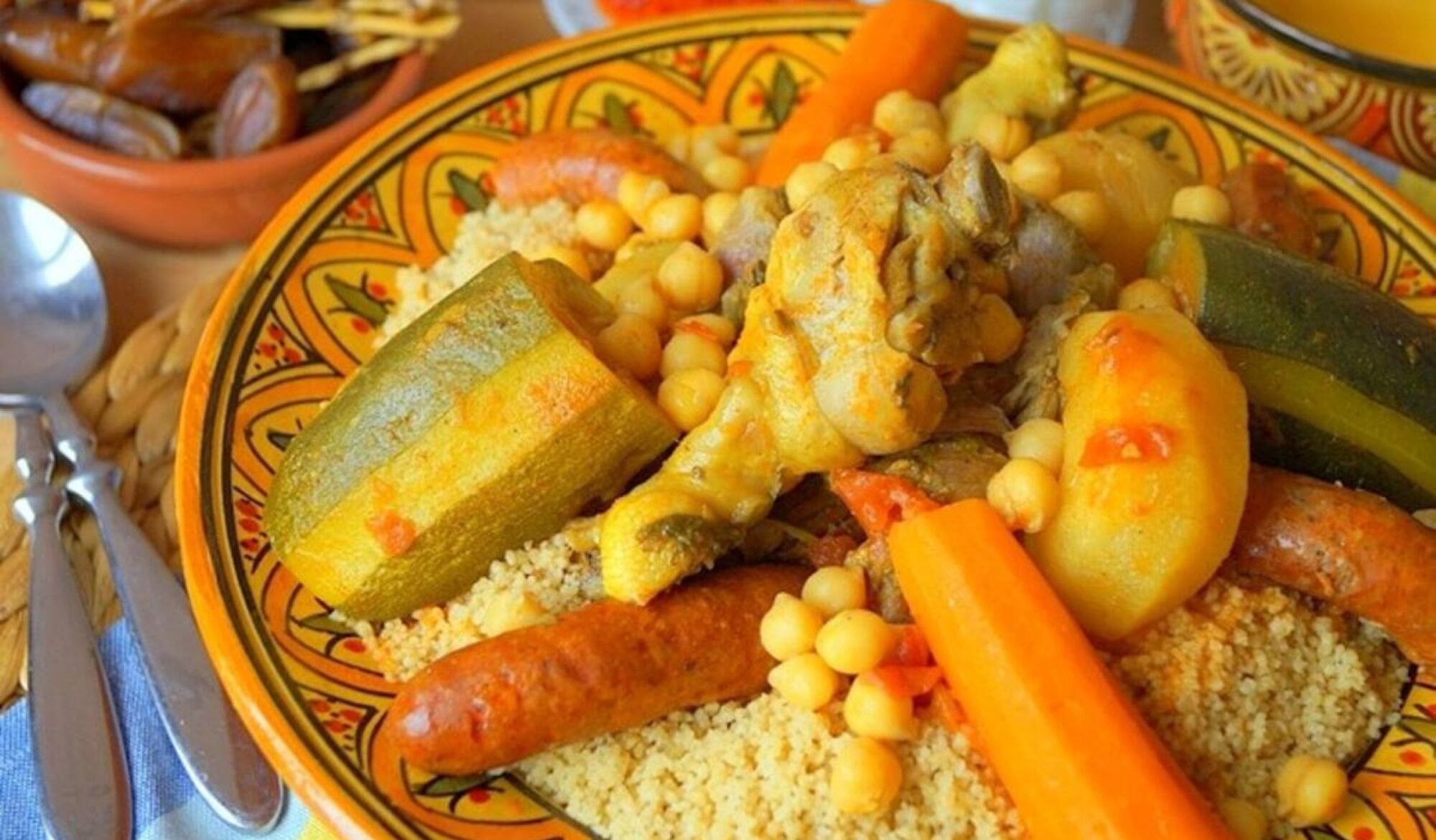 Une assiette de tajine marocain, accompagné de légumes et de couscous.