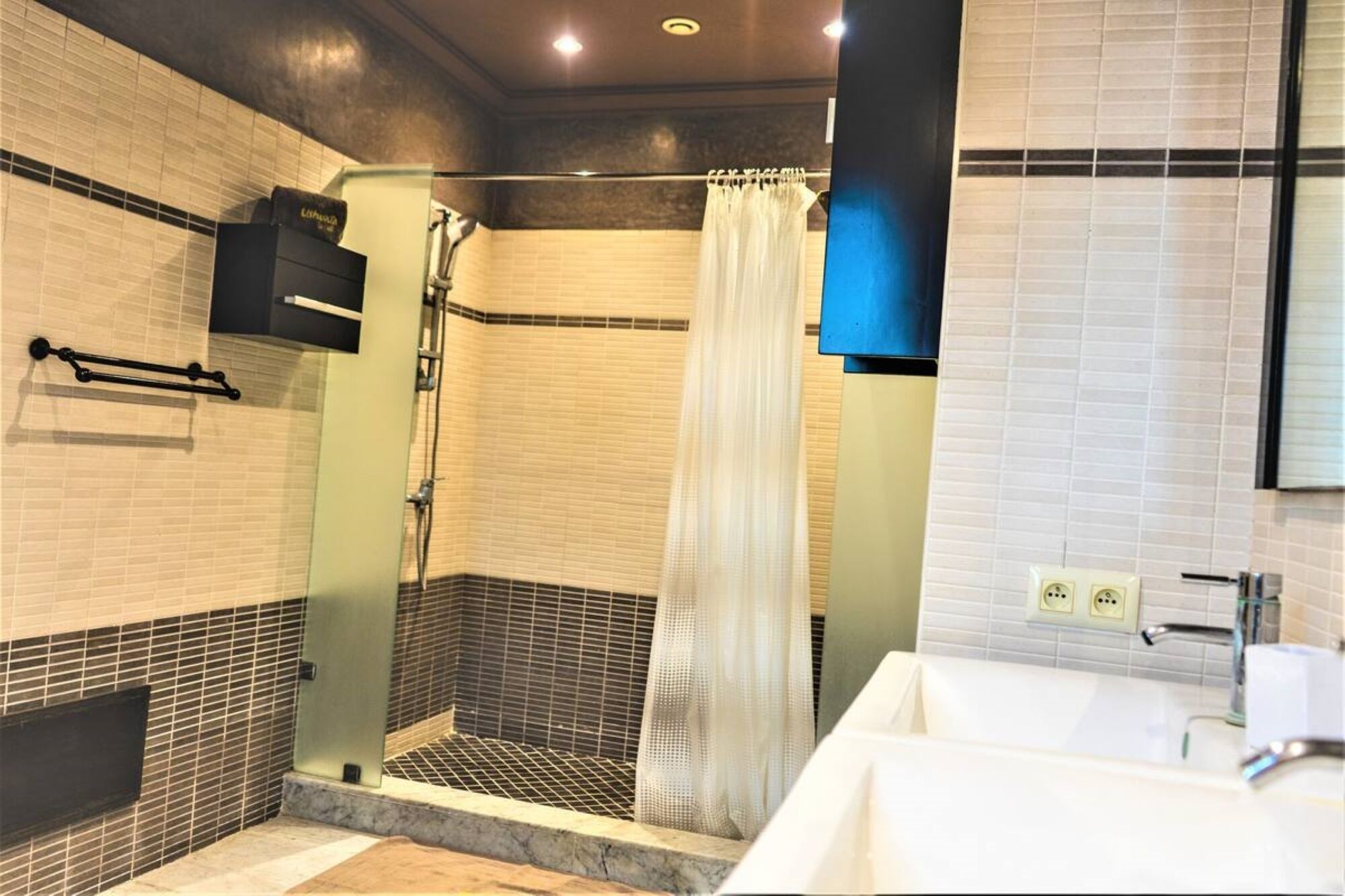 A modern bathroom with a glass-enclosed shower, a white bathtub, and a large mirror.