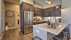 A modern kitchen with stainless steel appliances, dark wood cabinets, and a central island with bar stools. - Hike & Bike! Mtn-view Condo 1 Block to Main St (Winter Park)